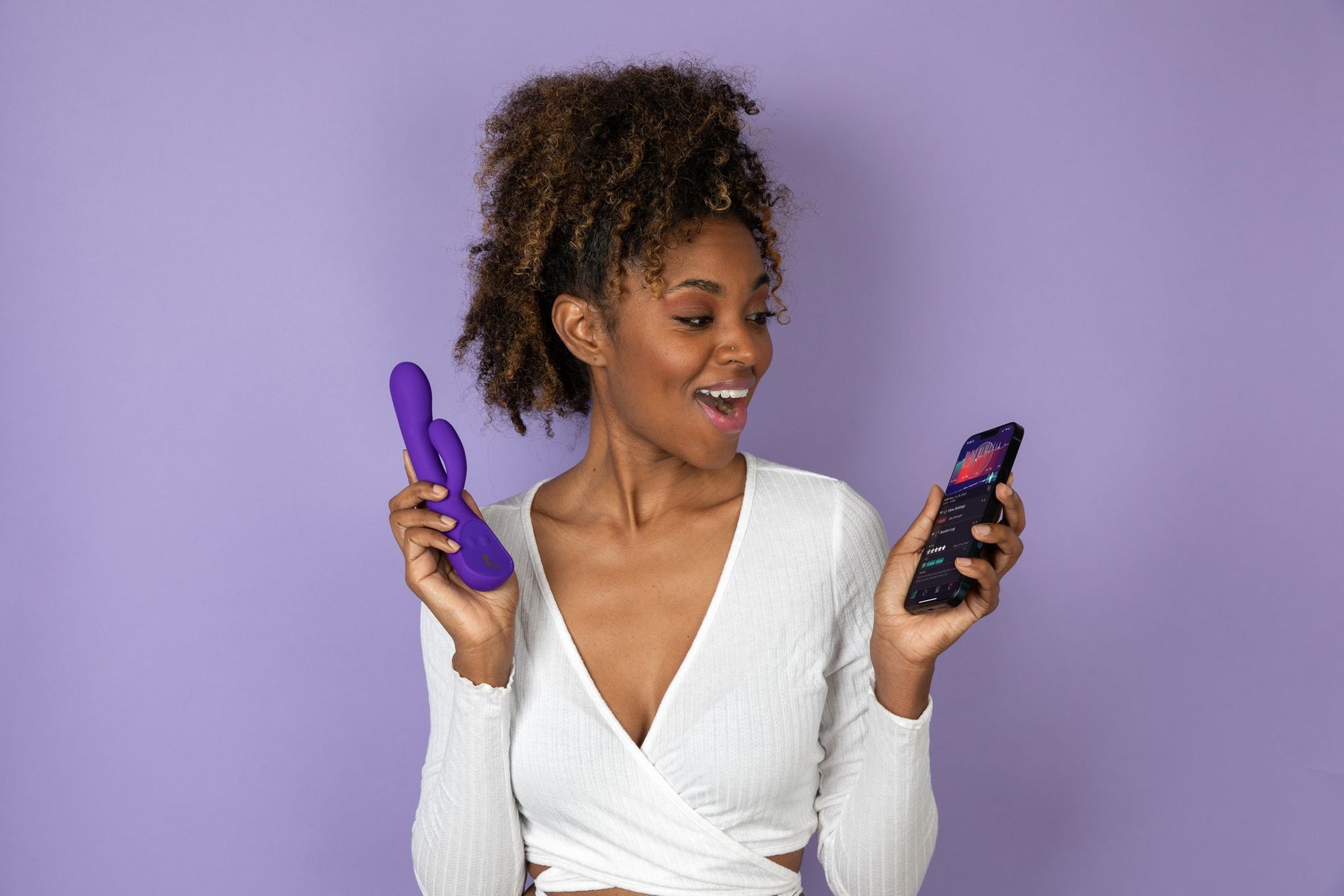 Woman holding purple Lioness Vibe and app in front of a purple background